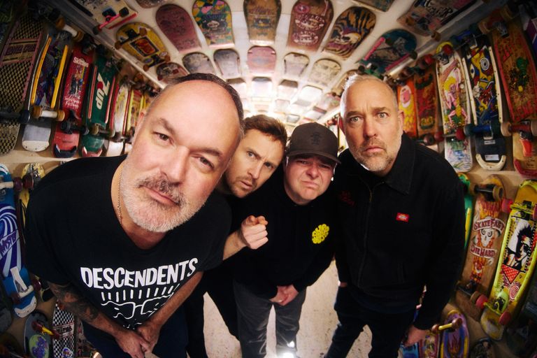 Fisheye lens shot of Australian punk rock band Bodyjar leaning toward the camera inside a room lined with vintage skateboard decks.